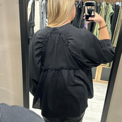 Blouse noire plus longues sur le derrière avec manches bouffantes et boutons